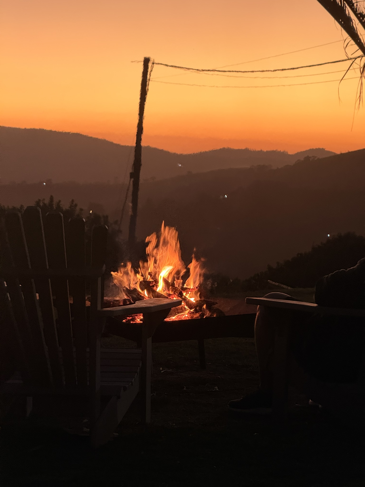 Fogueira acesa ao anoitecer, com a montanha ao fundo